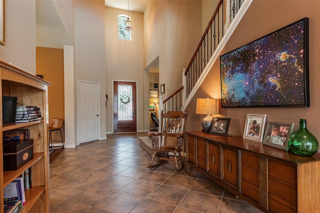 foyer featuring a towering ceiling and dark tile patterned flooring