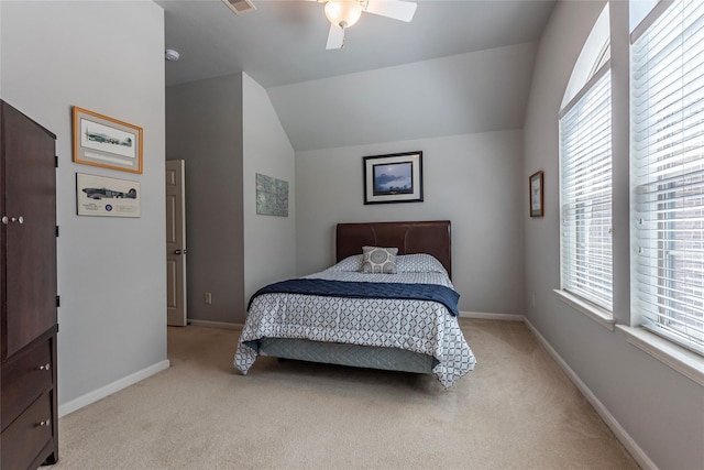 carpeted bedroom with multiple windows, ceiling fan, and vaulted ceiling