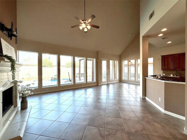 unfurnished living room with a fireplace, light tile patterned floors, a towering ceiling, and ceiling fan