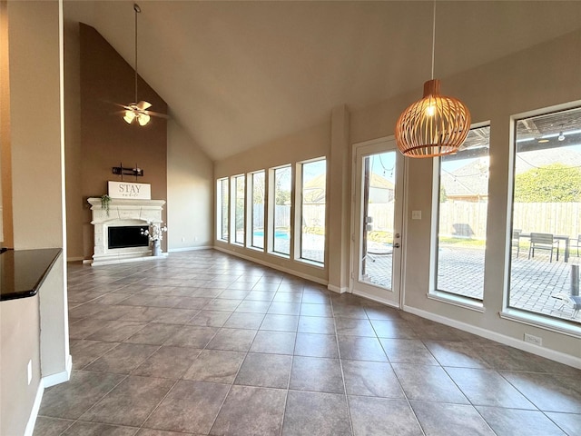 unfurnished living room with ceiling fan, plenty of natural light, high vaulted ceiling, and tile patterned flooring