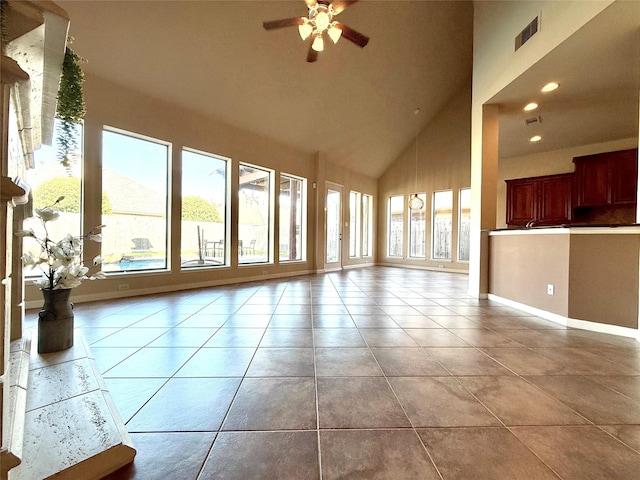 unfurnished living room with a wealth of natural light, ceiling fan, light tile patterned floors, and a high ceiling