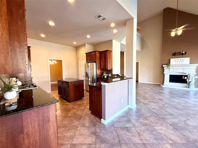 kitchen featuring sink, ceiling fan, stainless steel fridge, a kitchen island, and kitchen peninsula