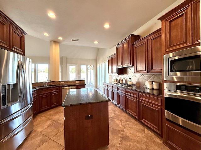 kitchen with appliances with stainless steel finishes, backsplash, dark stone countertops, a kitchen island, and lofted ceiling