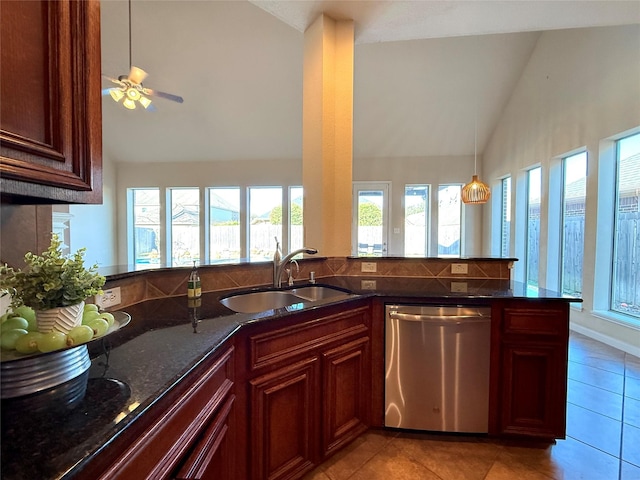 kitchen with kitchen peninsula, stainless steel dishwasher, dark stone counters, sink, and lofted ceiling