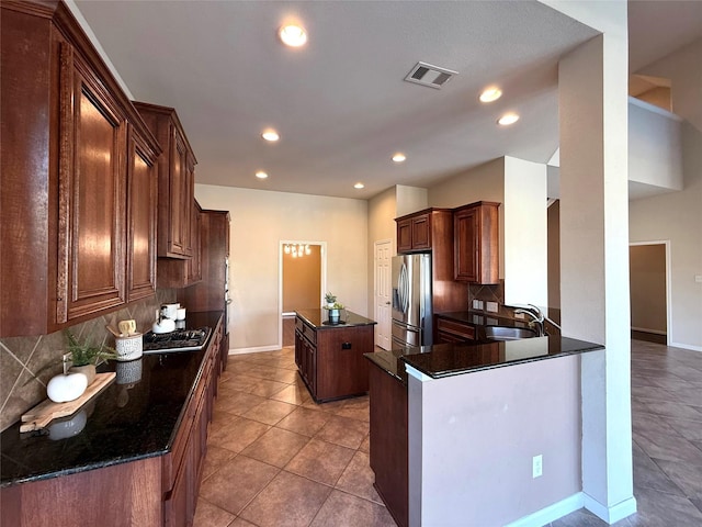 kitchen with dark stone counters, sink, tasteful backsplash, kitchen peninsula, and stainless steel appliances