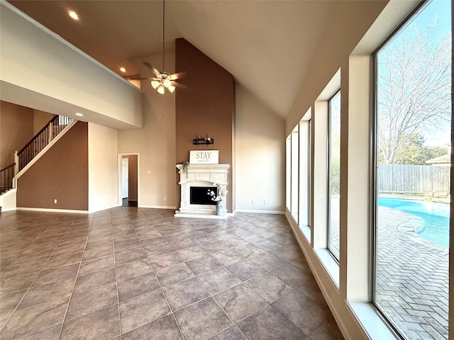 unfurnished living room with ceiling fan and a towering ceiling