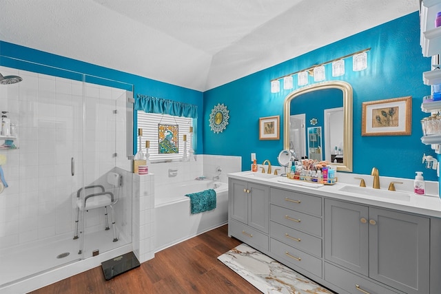 bathroom featuring vaulted ceiling, wood finished floors, a stall shower, and a sink