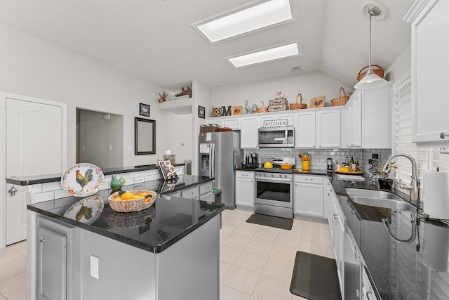 kitchen featuring stainless steel appliances, a kitchen island, a sink, white cabinets, and backsplash