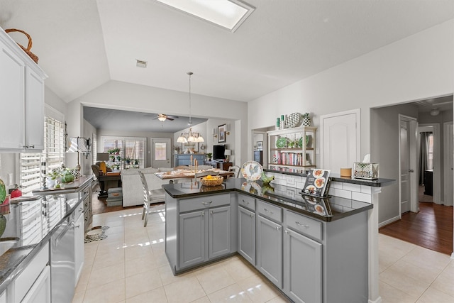 kitchen featuring dark countertops, gray cabinets, open floor plan, and light tile patterned flooring