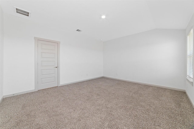 carpeted spare room featuring vaulted ceiling