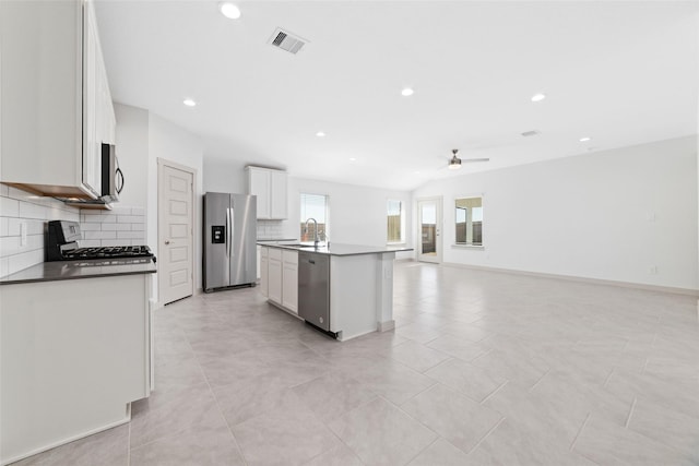 kitchen featuring stainless steel appliances, ceiling fan, sink, white cabinetry, and an island with sink