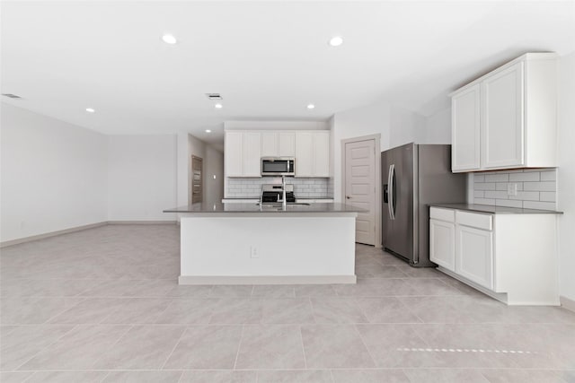 kitchen featuring white cabinets, backsplash, stainless steel appliances, and an island with sink