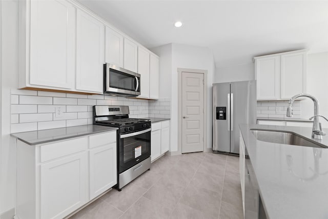 kitchen with white cabinets, sink, appliances with stainless steel finishes, and tasteful backsplash