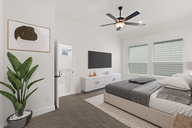 bedroom featuring multiple windows, dark colored carpet, ceiling fan, and ensuite bath