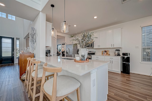 kitchen with pendant lighting, kitchen peninsula, hardwood / wood-style flooring, tasteful backsplash, and white cabinetry