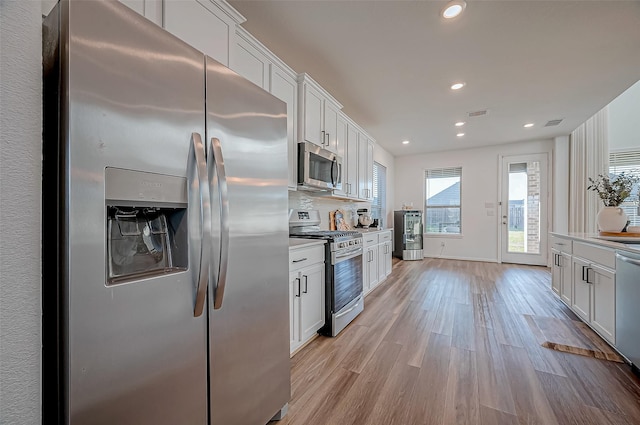 kitchen featuring appliances with stainless steel finishes, light hardwood / wood-style flooring, and white cabinetry