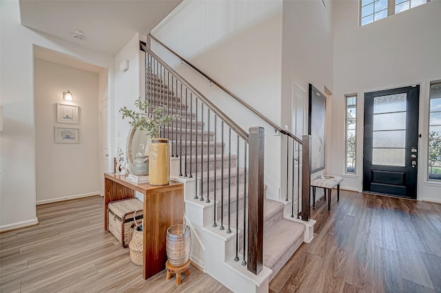 entryway featuring a towering ceiling and light hardwood / wood-style flooring