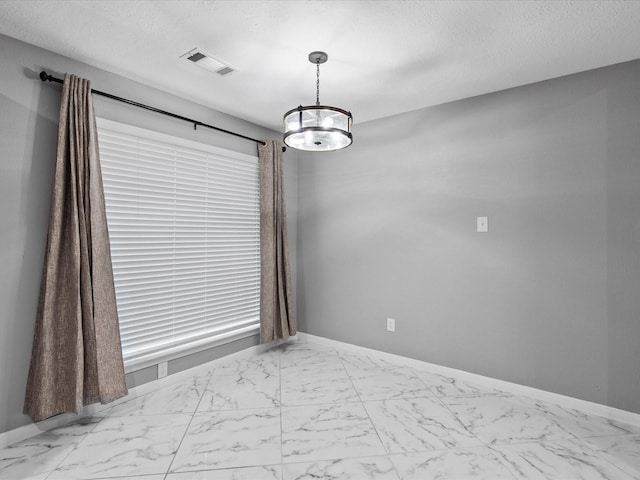 unfurnished room featuring a chandelier and a textured ceiling