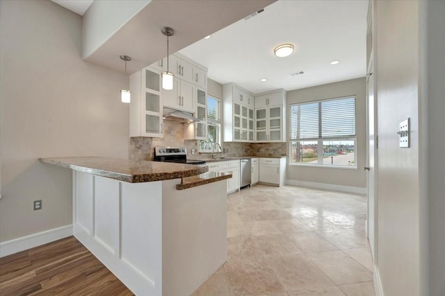 kitchen featuring kitchen peninsula, stainless steel appliances, sink, decorative light fixtures, and white cabinets