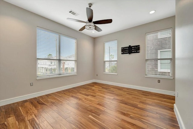 empty room with hardwood / wood-style flooring, ceiling fan, and a wealth of natural light