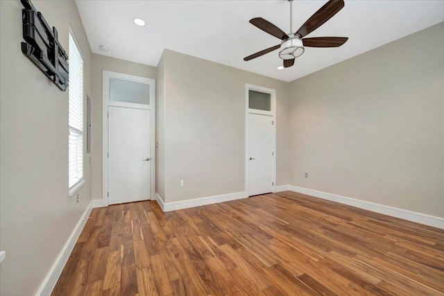 unfurnished bedroom with hardwood / wood-style floors, ceiling fan, and multiple windows