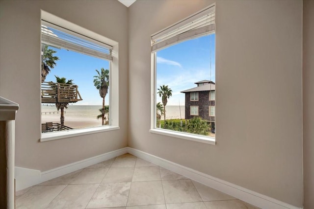 unfurnished room featuring light tile patterned floors and a water view