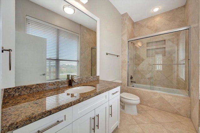 full bathroom featuring tile patterned floors, vanity, toilet, and combined bath / shower with glass door