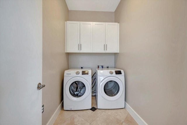 laundry area with cabinets, washing machine and clothes dryer, and light tile patterned flooring