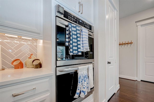 kitchen featuring backsplash, white cabinetry, dark hardwood / wood-style flooring, and stainless steel double oven