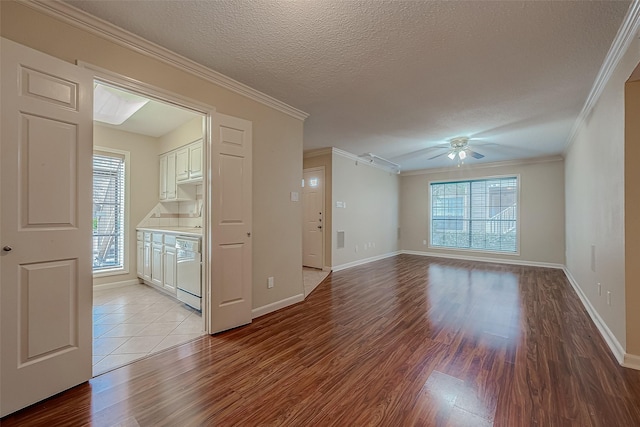 empty room with a textured ceiling, ceiling fan, light wood-type flooring, and crown molding