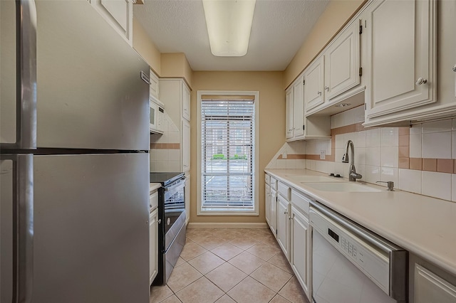 kitchen featuring appliances with stainless steel finishes, a textured ceiling, sink, white cabinets, and light tile patterned flooring