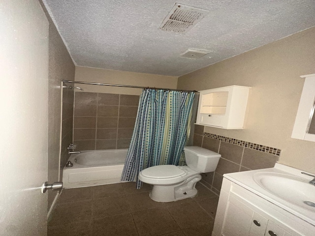 full bathroom featuring vanity, toilet, a textured ceiling, tile walls, and shower / tub combo with curtain