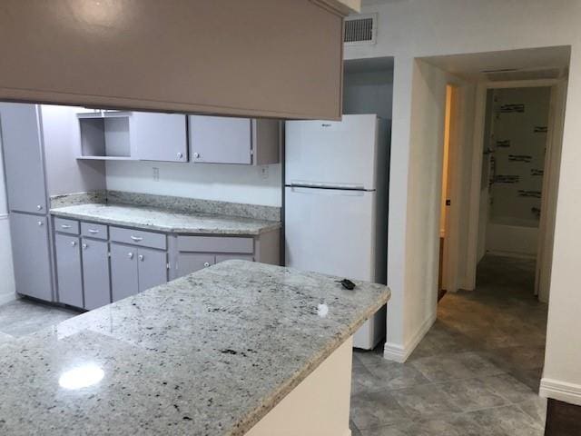 kitchen featuring white refrigerator and light stone countertops