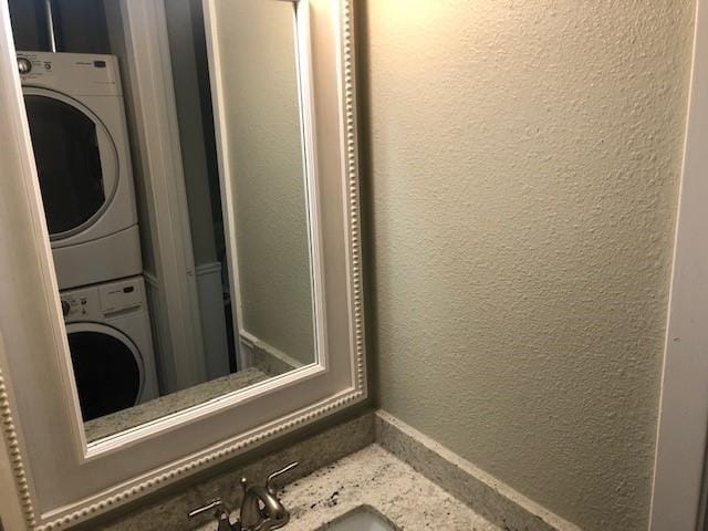 clothes washing area featuring stacked washer / drying machine and sink