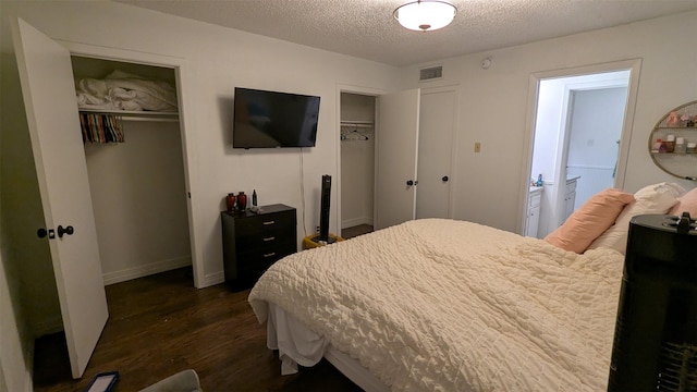 bedroom featuring ensuite bath, dark wood-type flooring, and a textured ceiling