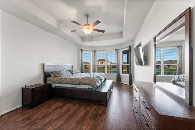 bedroom with a tray ceiling, ceiling fan, and dark wood-type flooring