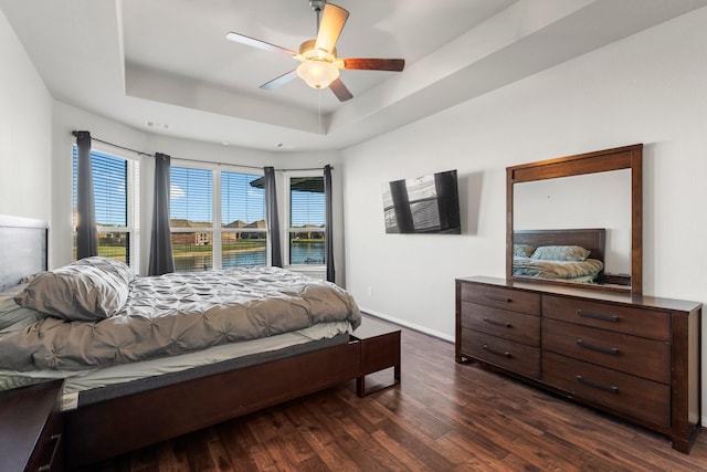 bedroom featuring a tray ceiling, ceiling fan, and dark hardwood / wood-style floors