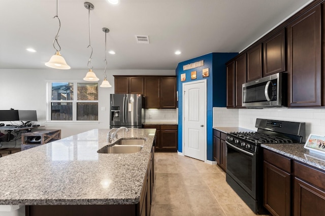 kitchen with sink, hanging light fixtures, stainless steel appliances, backsplash, and an island with sink