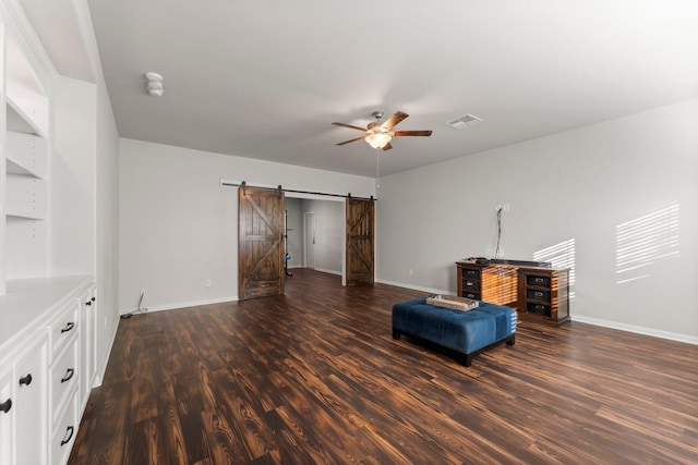 unfurnished room with a barn door, dark hardwood / wood-style floors, and ceiling fan