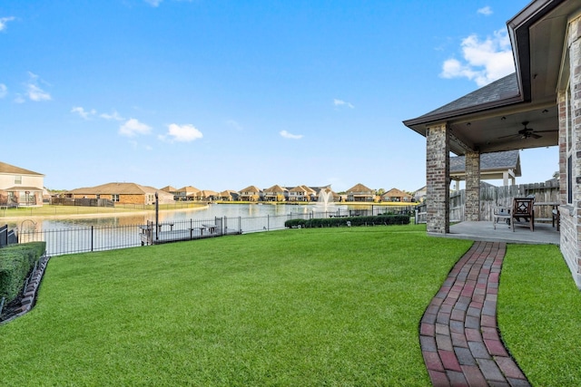 view of yard featuring ceiling fan, a water view, and a patio