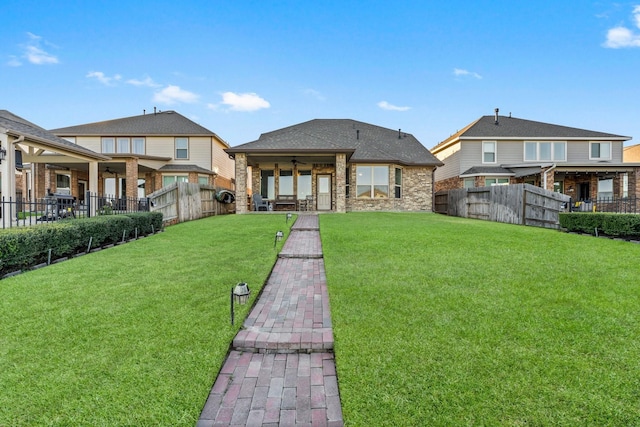 rear view of property featuring a yard and ceiling fan