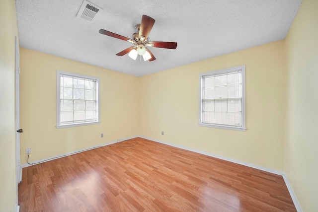 empty room featuring ceiling fan, light hardwood / wood-style floors, and a textured ceiling