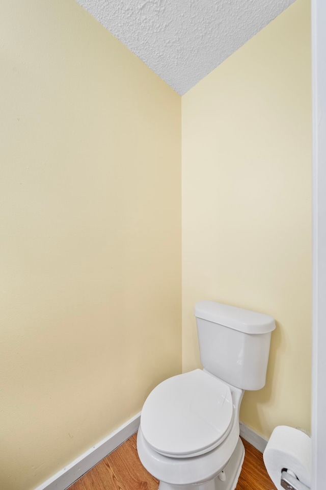 bathroom featuring a textured ceiling, hardwood / wood-style flooring, and toilet