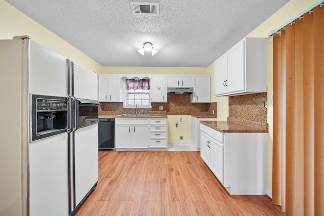 kitchen featuring white cabinetry, dishwasher, sink, white refrigerator with ice dispenser, and dark stone counters