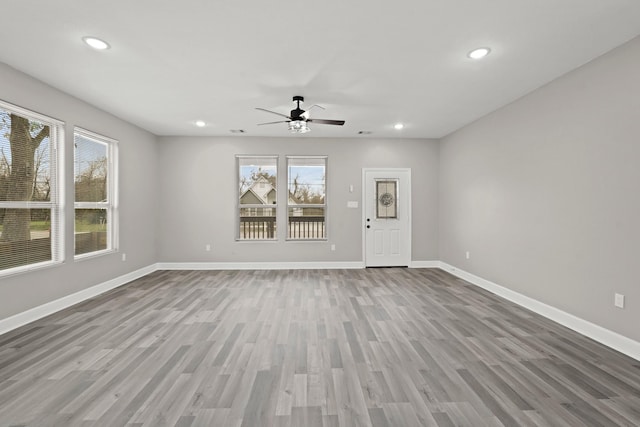 unfurnished living room with light wood-style floors, plenty of natural light, and baseboards