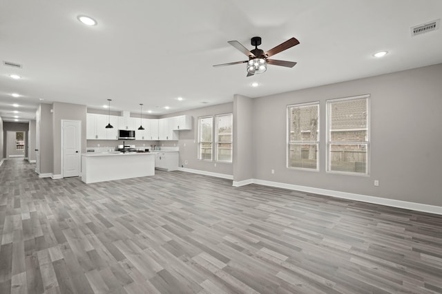 unfurnished living room with ceiling fan and light wood-type flooring