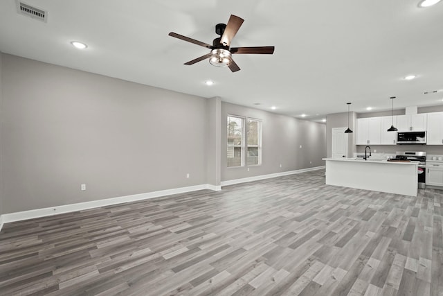 unfurnished living room featuring ceiling fan, sink, and light hardwood / wood-style floors