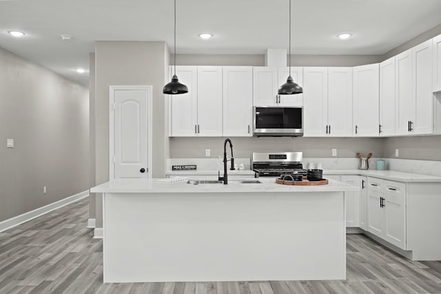 kitchen featuring white cabinetry, appliances with stainless steel finishes, a sink, and decorative light fixtures