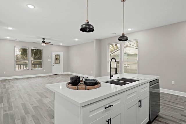 kitchen with open floor plan, decorative light fixtures, a kitchen island with sink, white cabinetry, and a sink