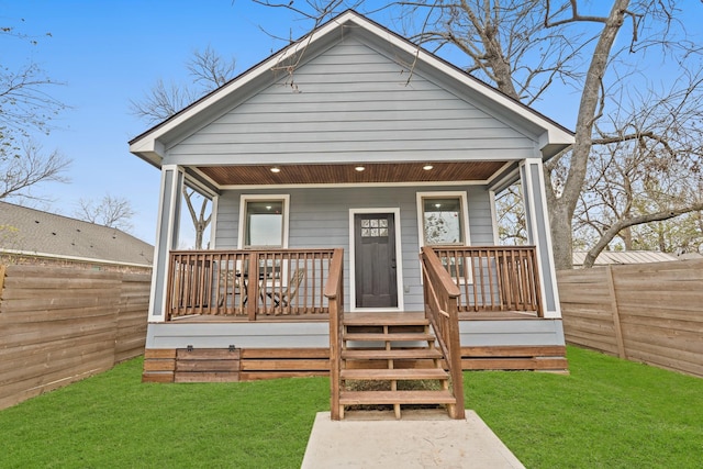 back of property featuring fence private yard, covered porch, and a yard